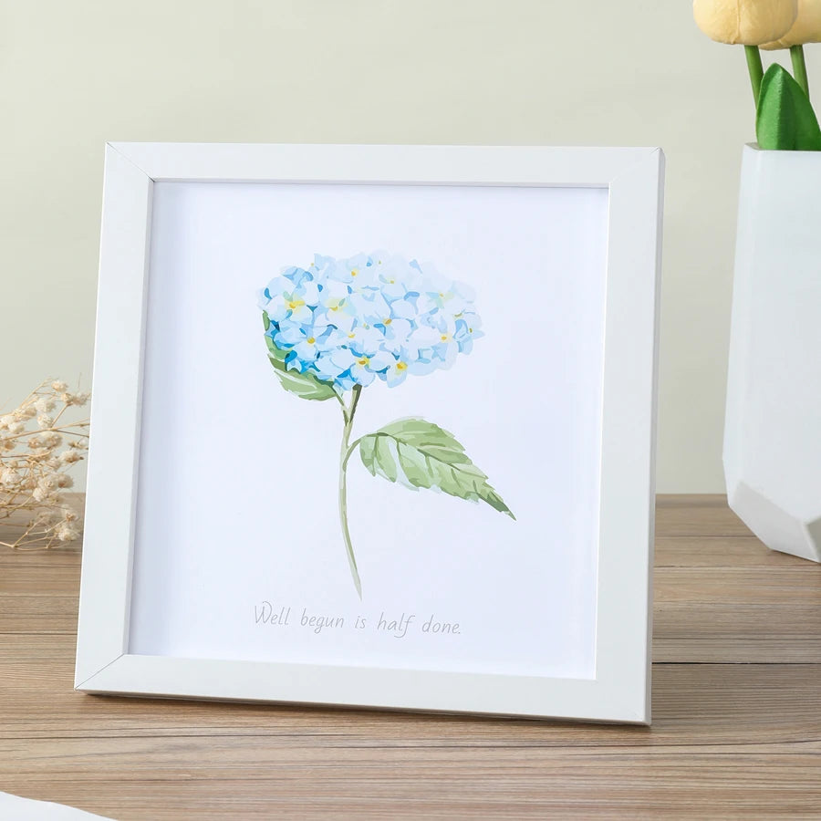 A white photo frame displays a watercolor illustration of blue hydrangeas on a white background.