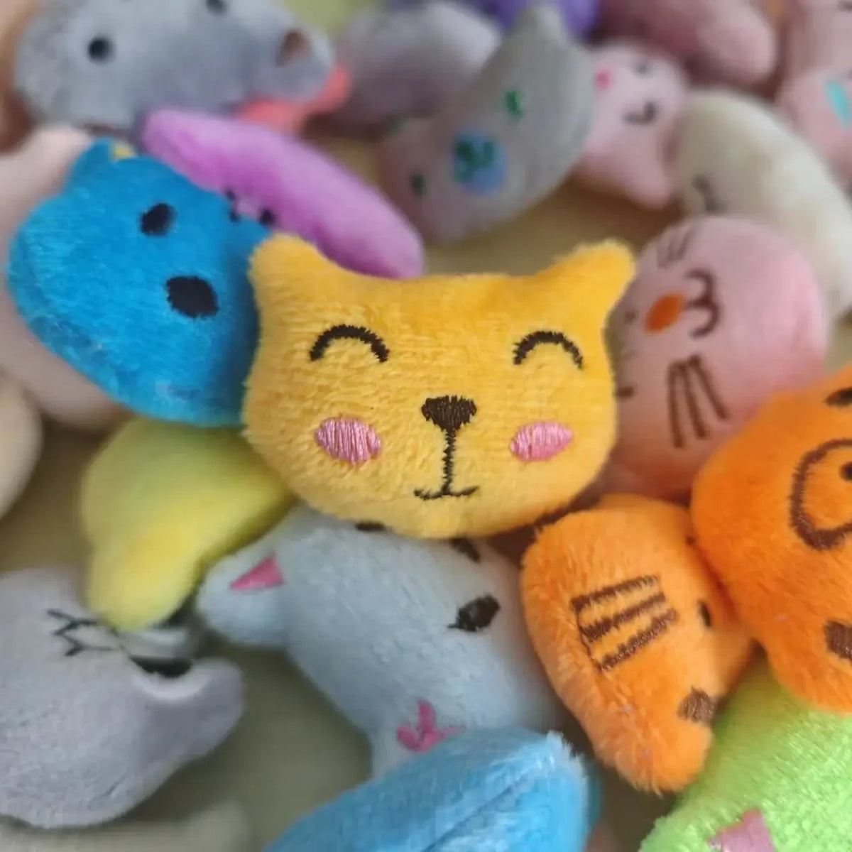 A close-up of various small, colorful animal plush dolls with various textures and shapes.