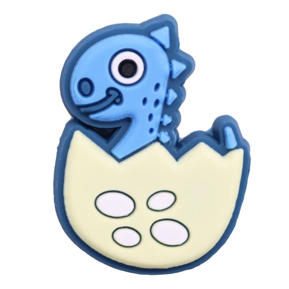 A set of twelve cartoon dinosaur PVC shoe charms featuring blue dinosaurs and a yellow egg shape.