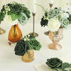 A collection of forest green and white foam roses with stems arranged in various golden vases.