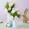 A bouquet of pink and green artificial foam roses and small eggs in a light blue vase