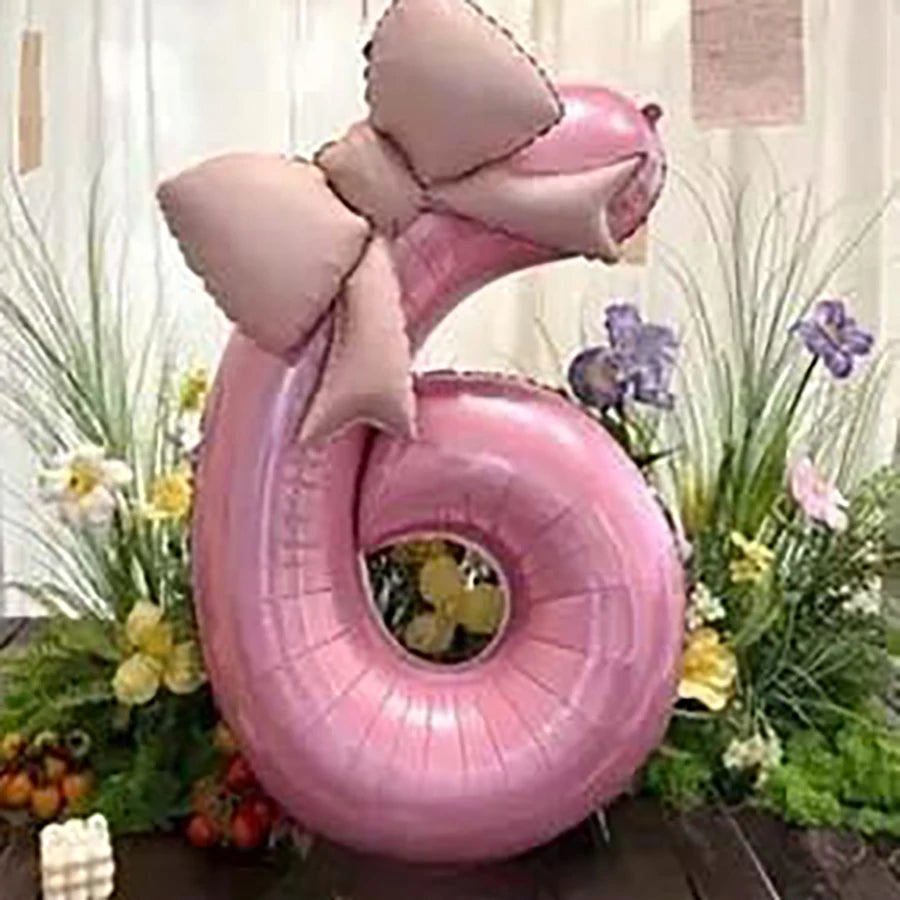 Pink 32-inch number balloons with matte bow decor set of two displayed with greenery and flowers