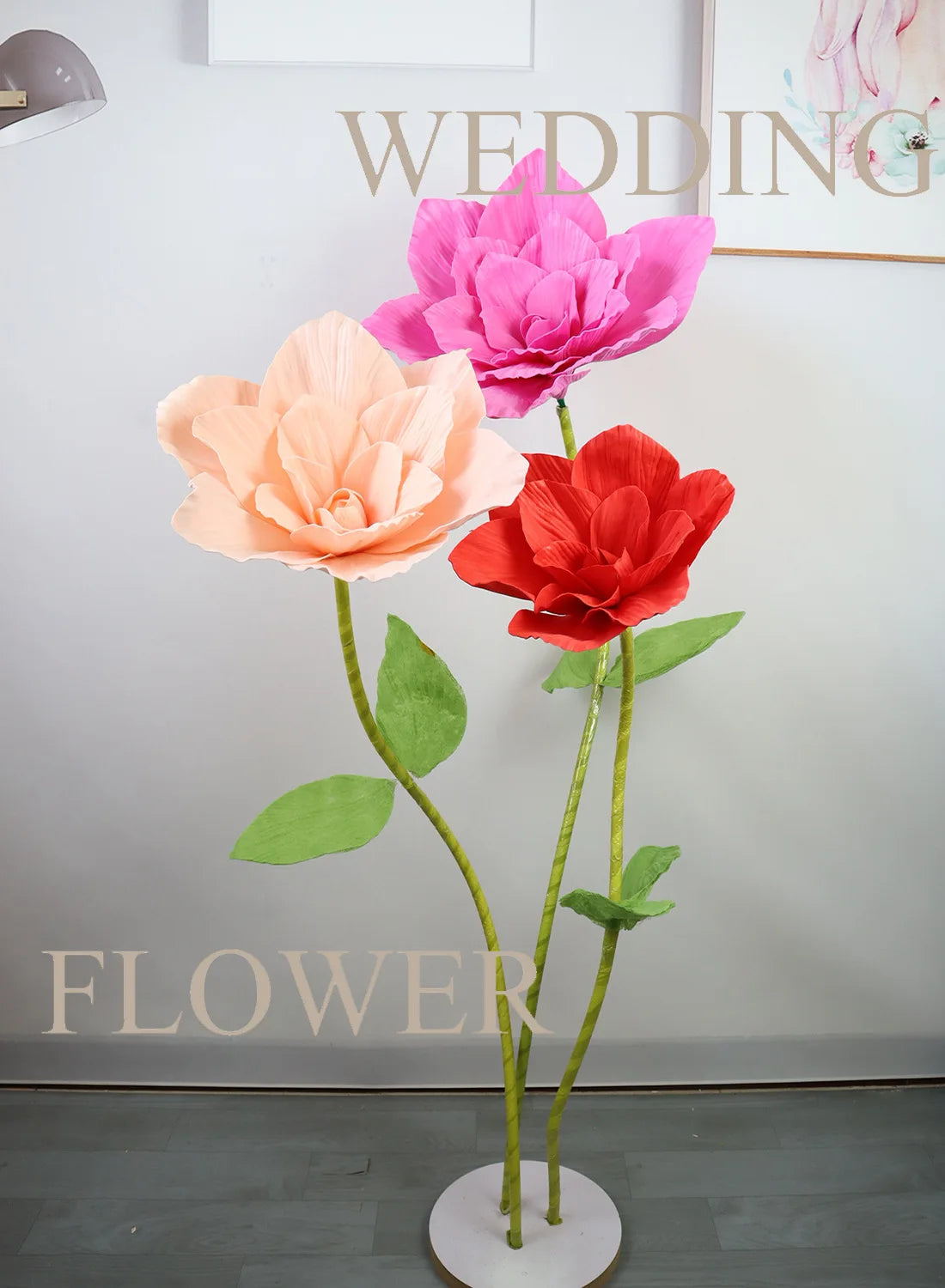 A vertical arrangement of pink and orange foam rose flowers on a white stand for wedding decor.