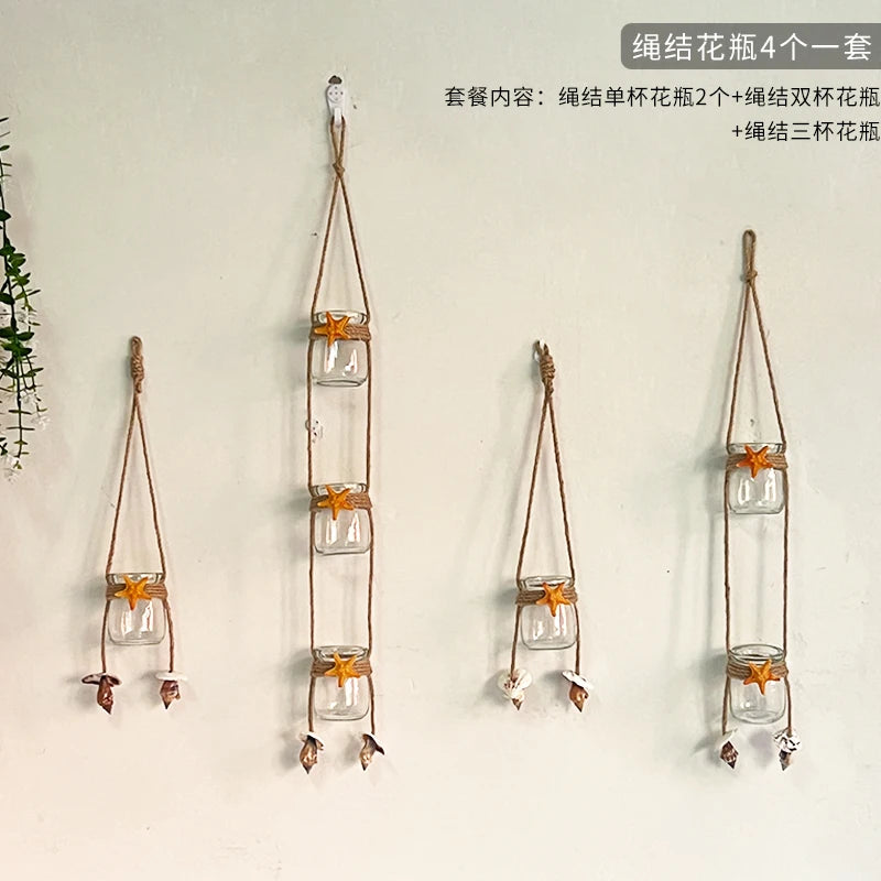 Three hanging decorative glass terrariums with small plants suspended by twine
