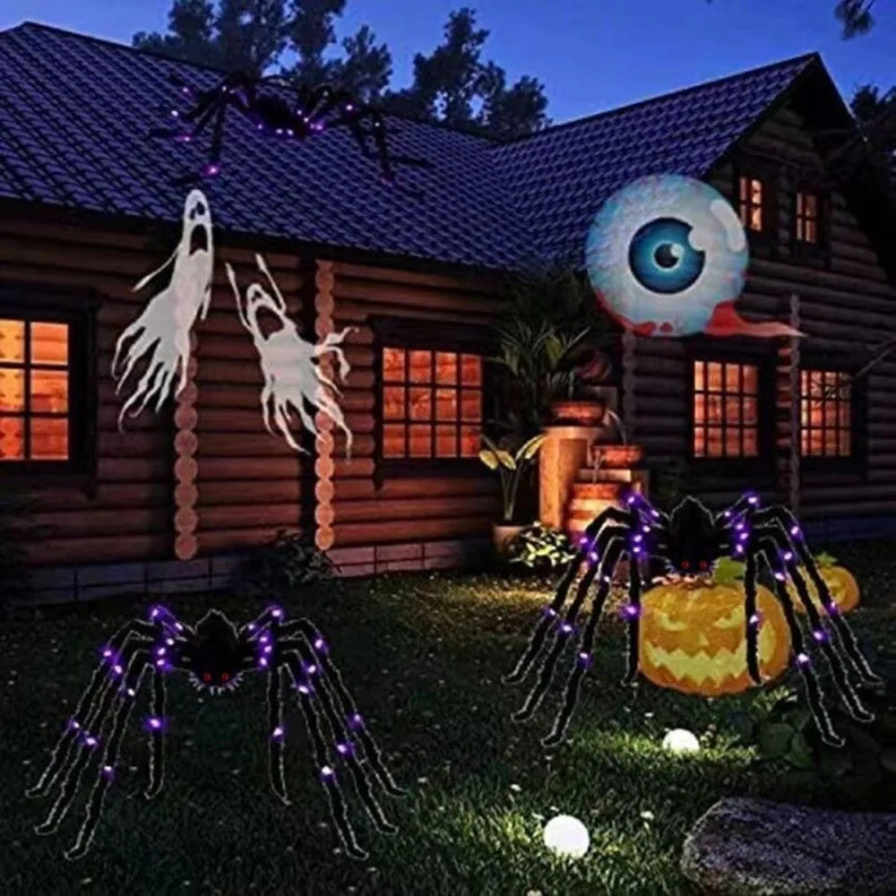 A wooden cabin decorated with glowing LED light-up spider figures and a large eye decoration in the dark.