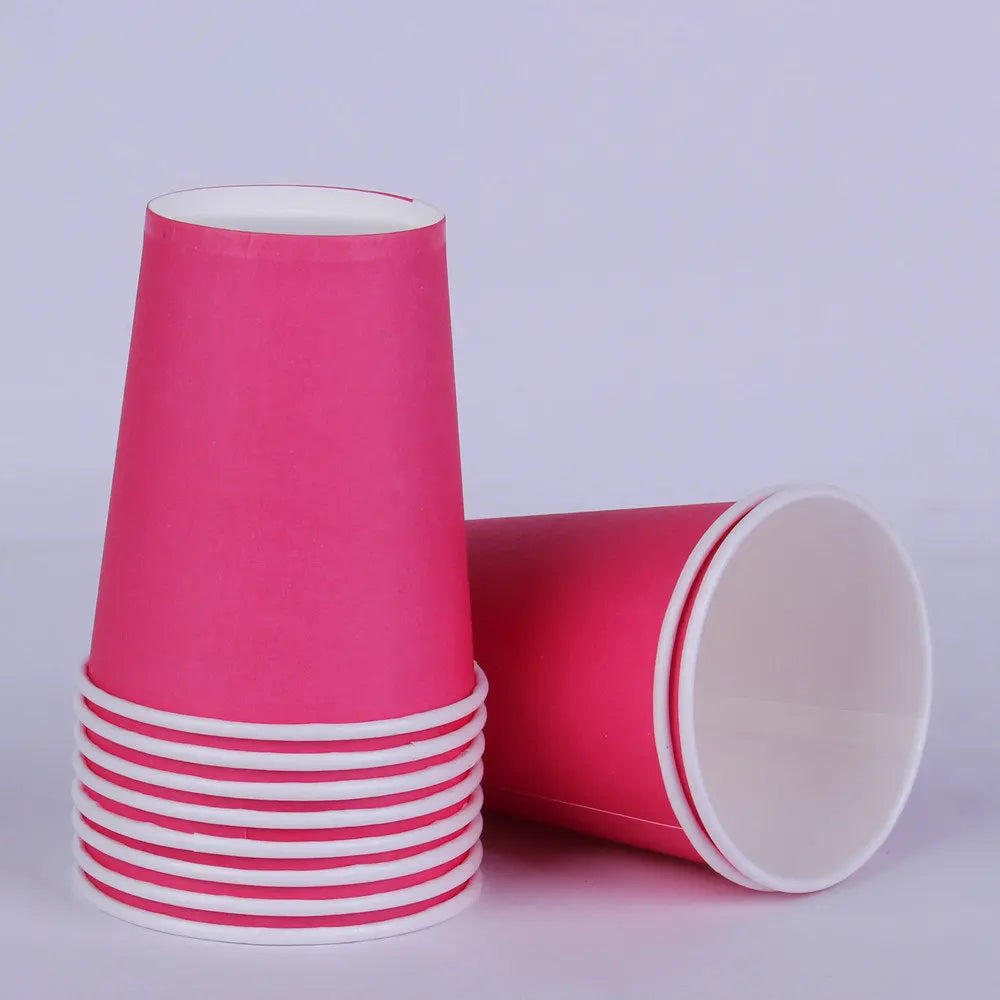 A stack of pink disposable cups with white stripes next to a solid pink cup.