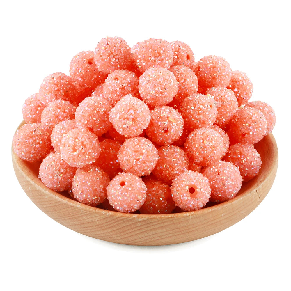 A pile of small, pink textured resin beads for jewelry making in a wooden bowl.