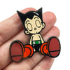 An enamel pin featuring a cartoon cat character with large eyes and a black and white design.