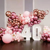 A large balloon arch decoration featuring metallic pink and rose gold latex balloons for a celebration.