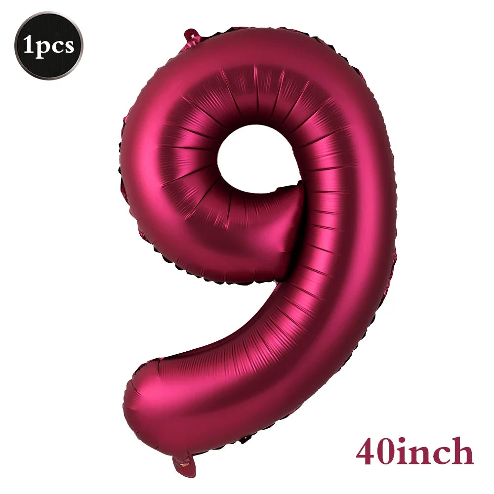 A large, shiny magenta foil number balloon shaped like the number 9.