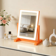 An orange LED makeup mirror with a rectangular frame and illuminated surface sits on a light-colored countertop.