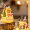 A festive Christmas gingerbread house resin ornament set displayed on a book with warm glowing lights.