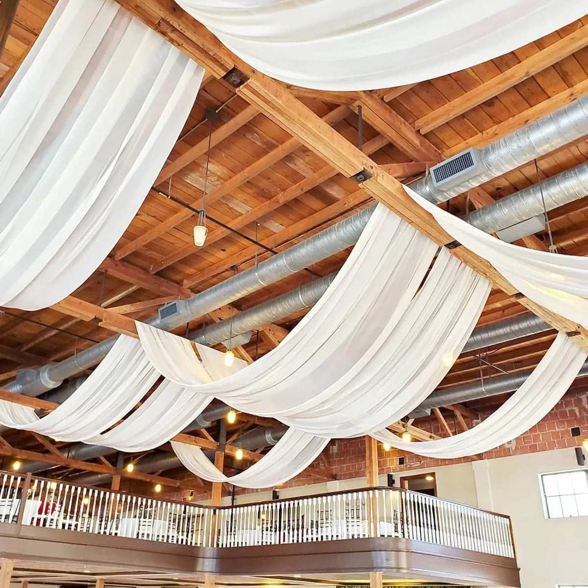 Tissu de chiffon blanc élégant drapé, suspendu d'une structure en bois pour une toile de fond d'événement.