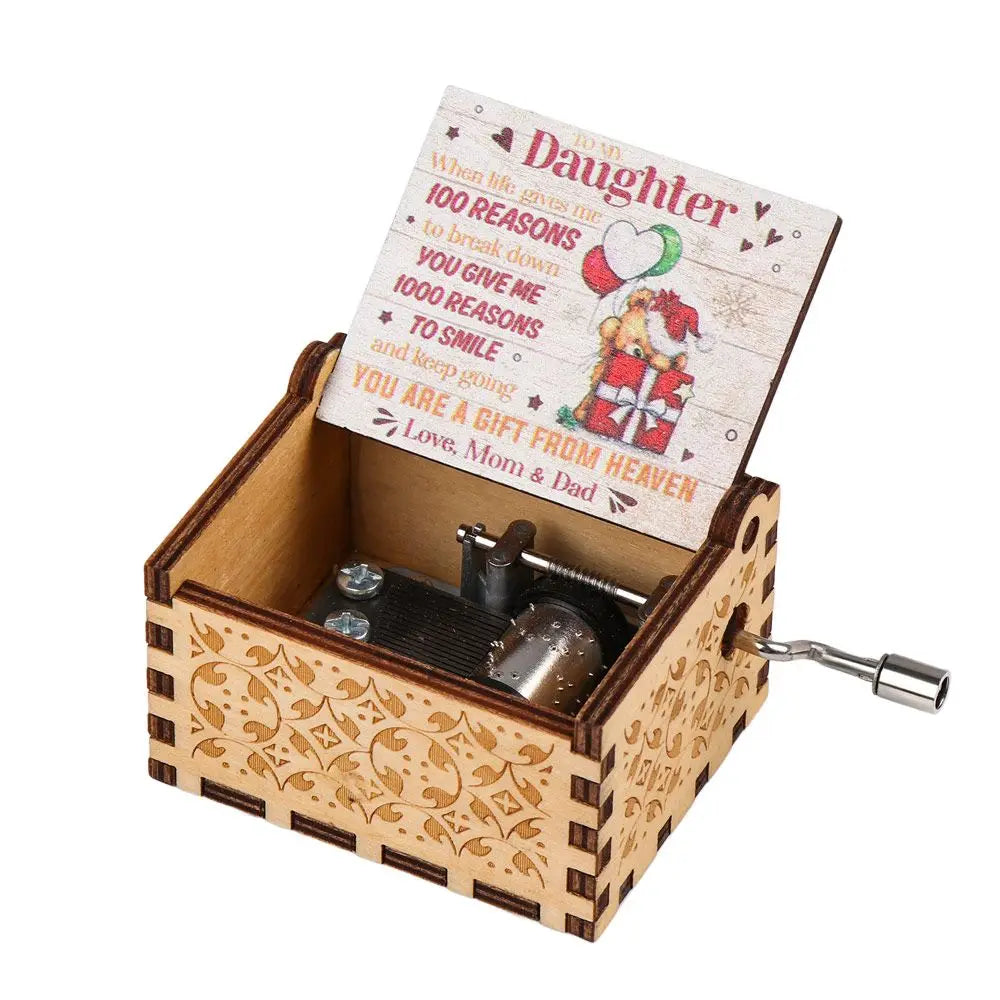 A vintage hand-cranked wooden music box with a lid featuring text about a daughter and a gift from heaven.