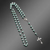 A silver necklace featuring small pale green beads and a vintage cross pendant.