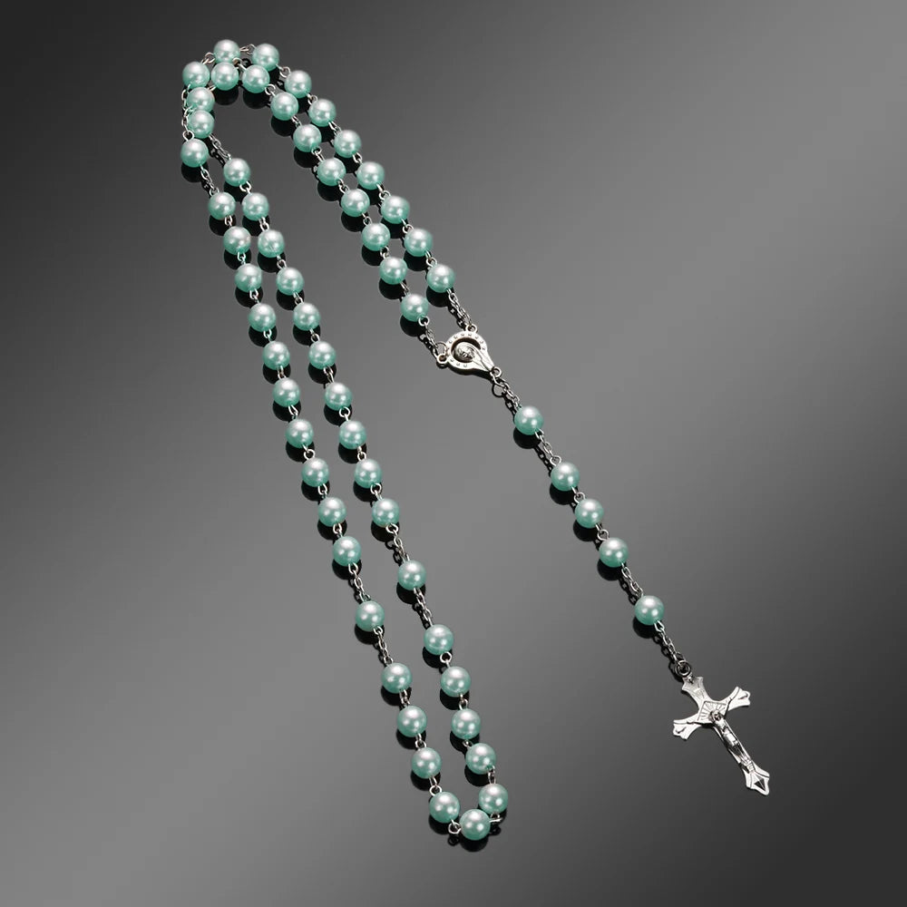 A silver necklace featuring small pale green beads and a vintage cross pendant.