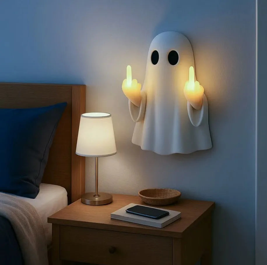 A white ghost figurine lamp with a warm glow mounted on a wall above a wooden nightstand.
