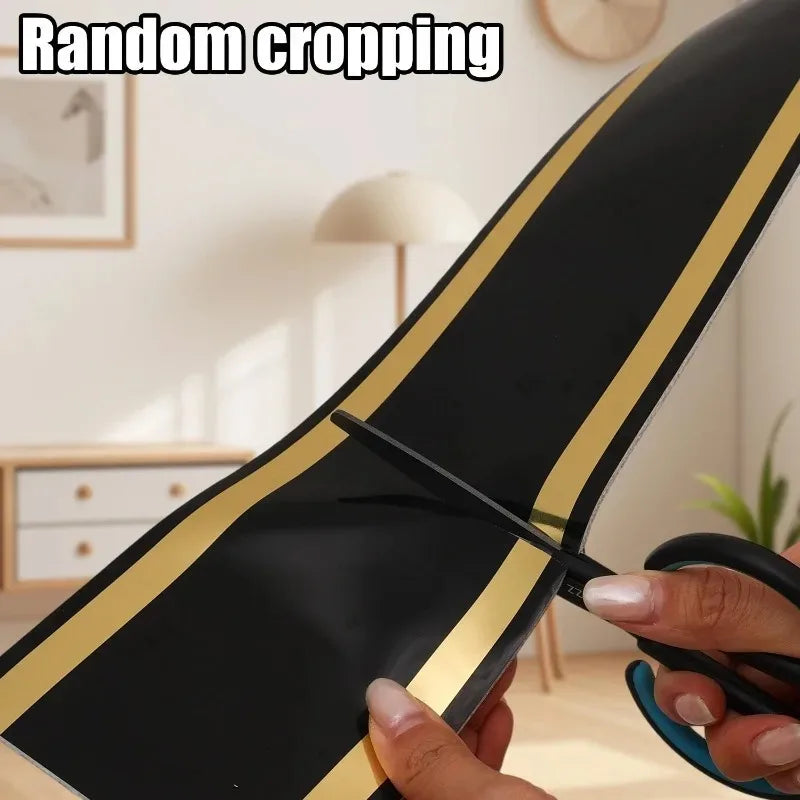 A hand is using scissors to perform random cropping on a black and gold self-adhesive PVC skirting board trim.