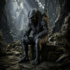 A dark sci-fi figurine of a hooded hunter sits on rough terrain in a dimly lit, jungle-like environment.