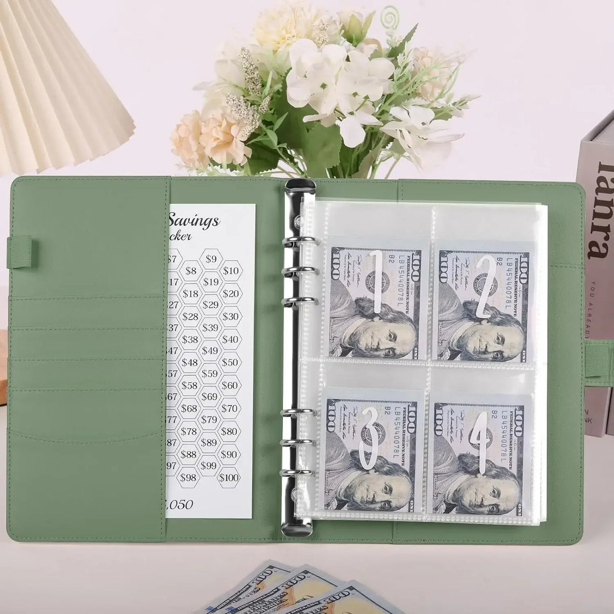 Un archivador A5 verde con bolsillos transparentes para almacenar diversas denominaciones de moneda estadounidense y una comp
