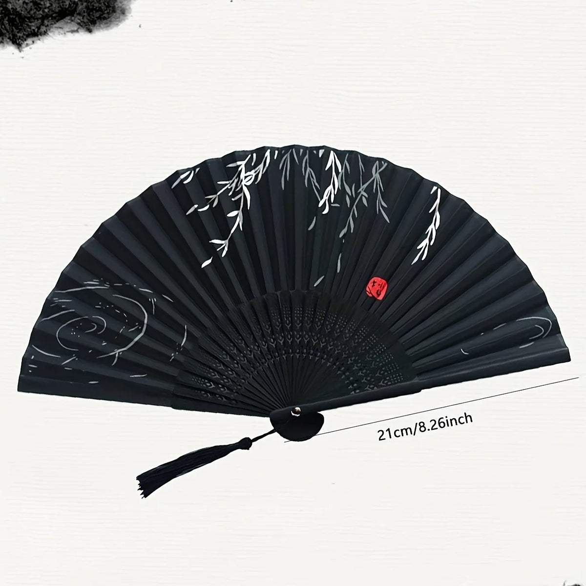 A black hand folding fan decorated with white leafy patterns.
