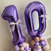 Purple foil number balloon shaped like the number 10 with a bow and clustered balloons