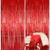 Two panels of vertical metallic red foil fringe curtains, one panel is being held by a hand.