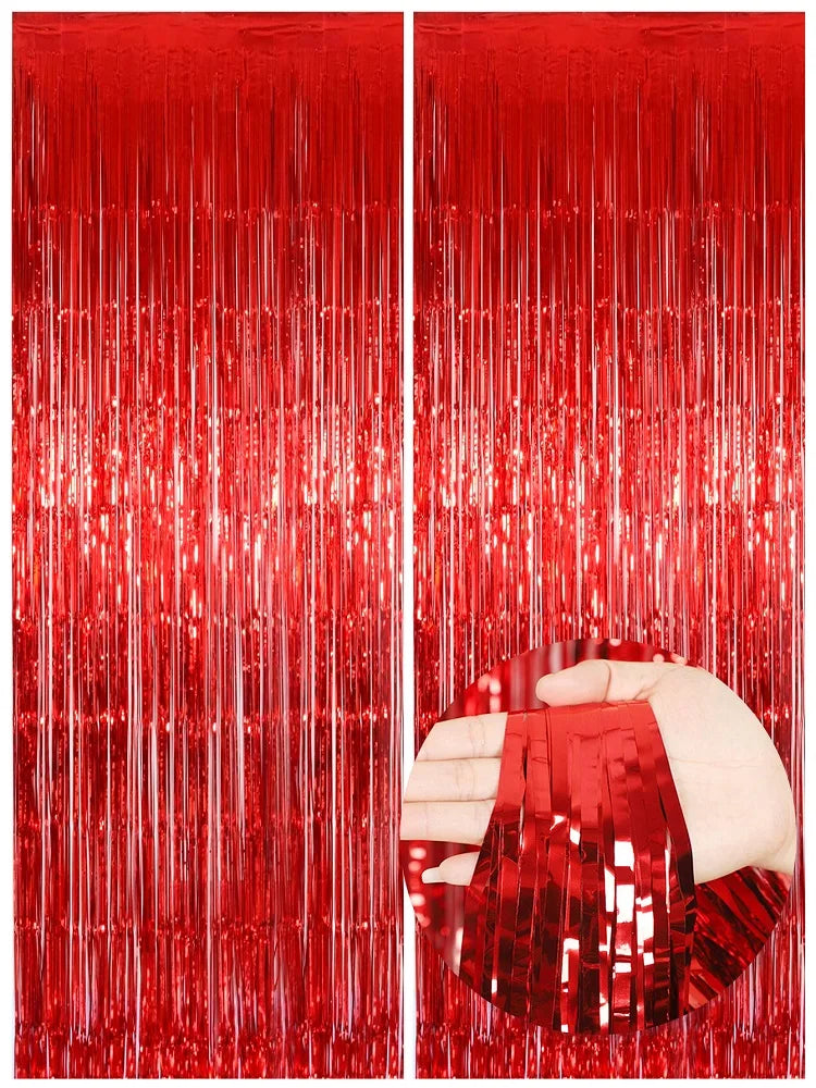 Two panels of vertical metallic red foil fringe curtains, one panel is being held by a hand.