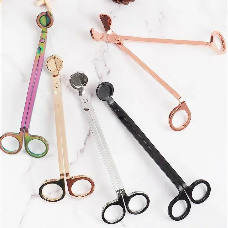 A collection of various stainless steel candle wick trimmer scissors in pink, gold, and black.