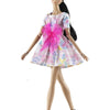 A handmade doll dress gown featuring pink and purple floral patterns with bright pink glitter accents.