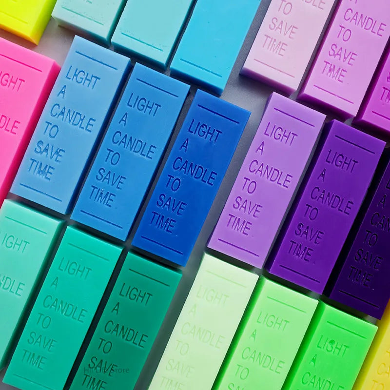 A collection of brightly colored, rectangular candle dye colorants in various shades of pink, blue, purple, and green.