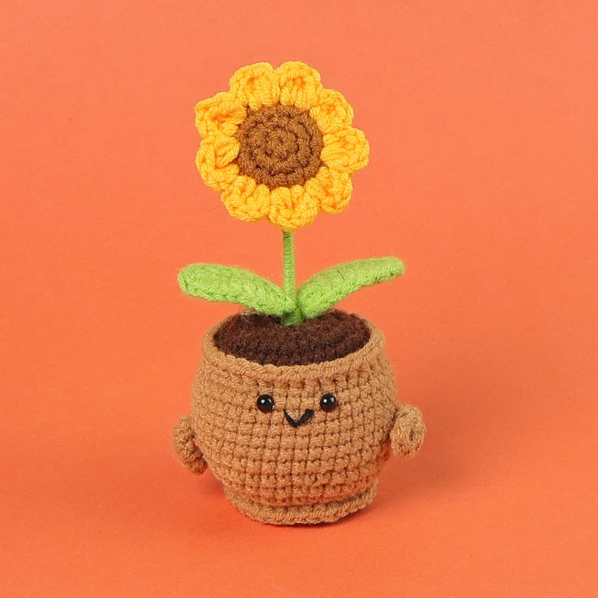 Handmade crochet sunflower desk companion with a smiling face, featuring yellow petals and green leaves.