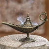 Brûleur d'encens en métal antique avec une finiale décorative, émettant de la fumée sur une surface de pierre.
