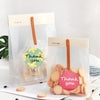 Klares Verpackung zeigt runde Blumen-Dankeschön-Sticker neben einem Stück Papier.