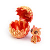 A golden, textured dragon egg is cracked open to reveal a small, orange-colored dragon toy.