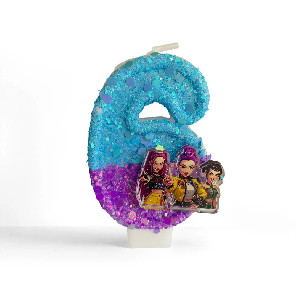 A large, glittery blue number two candle decorated with purple and pink iridescent confetti and images of characters.