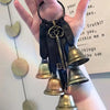 Une main tient une clé de poignée de porte de sorcière en bronze vintage, avec des carillons suspendus à un cordon en cuir no
