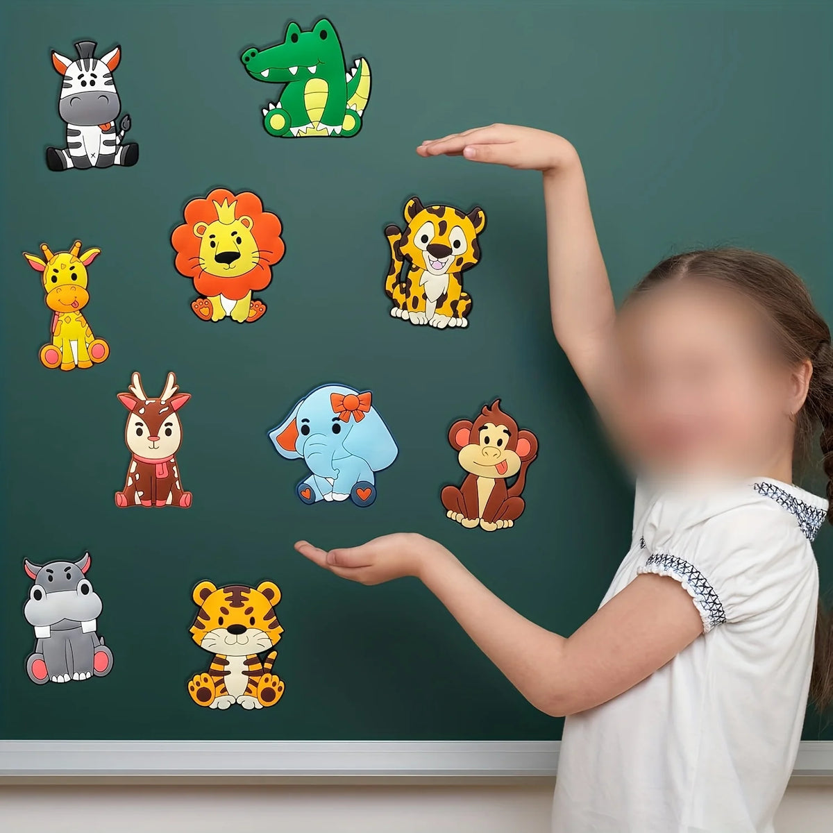 A girl is presenting a set of ten colorful cartoon animal fridge magnets on a dark green chalkboard.