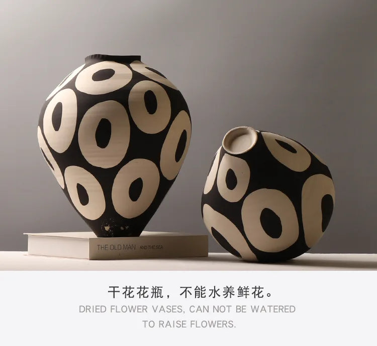 Two black and beige ceramic vases with geometric circle designs on a light gray background.