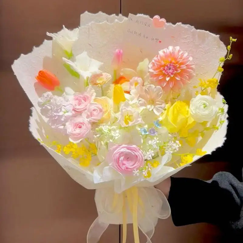 A bouquet of pink, yellow, and white flowers wrapped in decorative paper for gifts and weddings.
