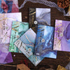 A collection of gradient wash retro decorative paper cards in purple, blue, and gold tones arranged on a dark wooden surface.