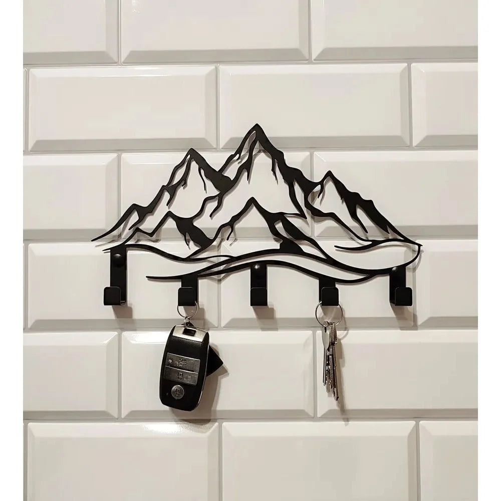 Black silhouette of a mountain range mounted on a white tiled wall with an iron key holder and hooks