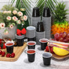 A collection of mini plastic shot cups in black and white stripes arranged on a wooden board with fresh fruit.