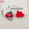 Two red resin cabochons shaped like a Christmas tree and a truck, used for DIY crafts.