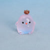 A small, translucent pink and blue resin chicken ornament with a bronze-colored crest.