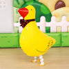 A yellow cartoon duck foil balloon standing in front of a green and white picket fence backdrop.