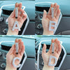 A set of crystal letter keychain charms A, B, and D held in a person's hand against a car interior background.