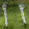 A pair of realistic white skeleton arm stakes used for Halloween lawn decor standing in green grass.
