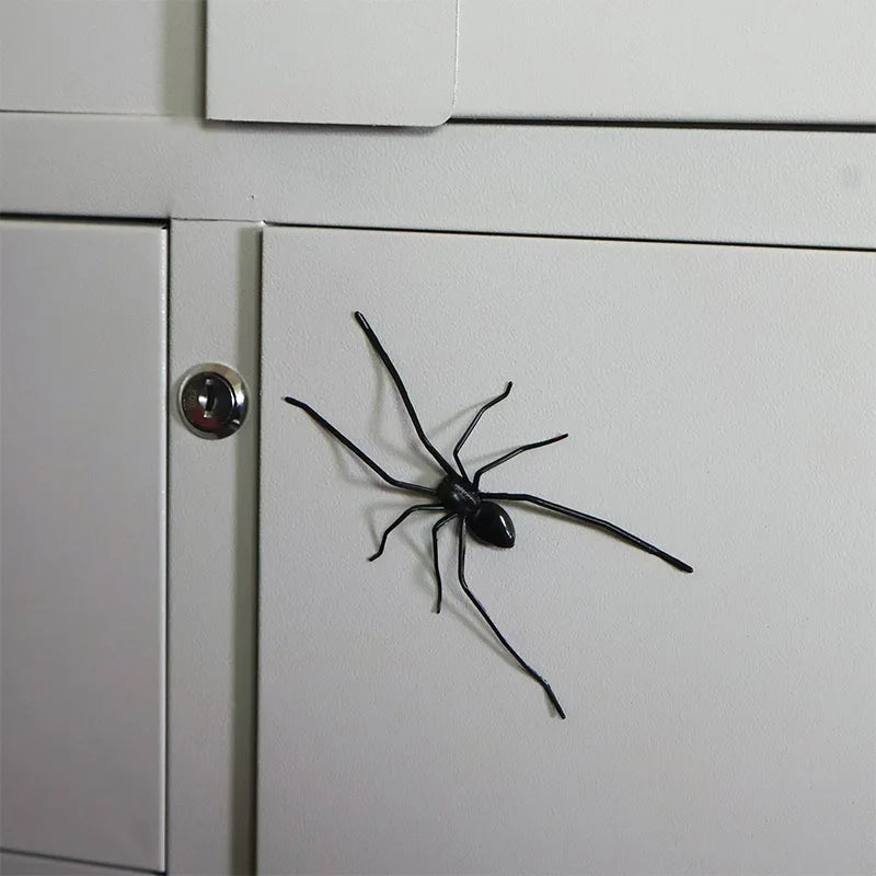 A black spider is affixed to a white refrigerator door, used as a realistic horror decor magnet.