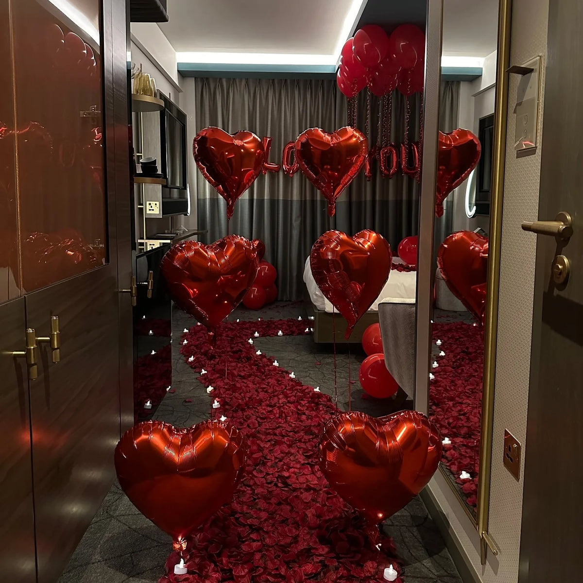 A row of red heart-shaped foil balloons spelling out I LOVE YOU displayed in a room.